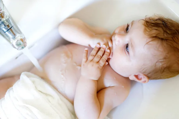 Schattige schattig baby nemen bad in wassen gootsteen en waterkraan pak. — Stockfoto