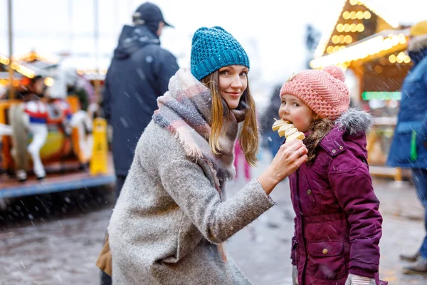 Jeune mère et fille mangeant des fruits couverts de chocolat blanc sur brochette sur le marché de Noël allemand traditionnel — Photo