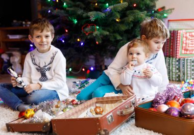 İki küçük çocuk çocuklar ve bebek kız eski vintage oyuncak ve topları ile Noel ağacı süsleme.
