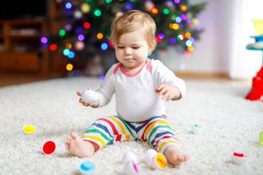 Evde ya da çocuk odasında eğitici oyuncaklarla oynayan sevimli, güzel bir kız bebek. Mutlu sağlıklı çocuk renkli şekil ayırıcı oyuncakla eğleniyor. Çocuk farklı yetenekler öğreniyor
