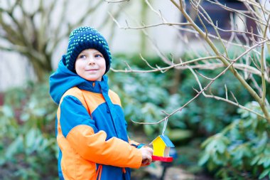 Küçük çocuk çocuk kuş evi kış aylarında beslenme için ağaç üzerinde asılı