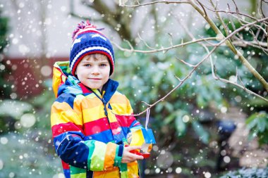 Küçük çocuk çocuk kuş evi kış aylarında beslenme için ağaç üzerinde asılı
