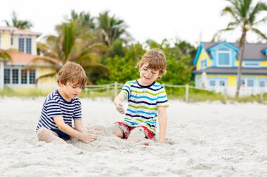 İki küçük çocuk tropik sahilde eğleniyor.