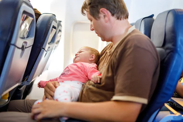 Jonge moe vader en dochter met huilende baby tijdens vlucht op vliegtuig op vakantie te gaan — Stockfoto