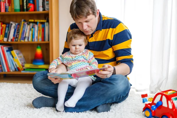 Νεαρός πατέρας ανάγνωση βιβλίων με την κοπέλα του χαριτωμένο αξιολάτρευτο μωρό κόρη — Φωτογραφία Αρχείου