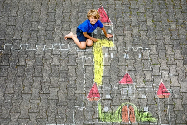 Menino desenhando castelo de cavaleiro e fortaleza com giz colorido. Criança pré-escolar feliz se divertindo com a criação de imagem de giz. Lazer criativo para crianças e crianças no verão — Fotografia de Stock