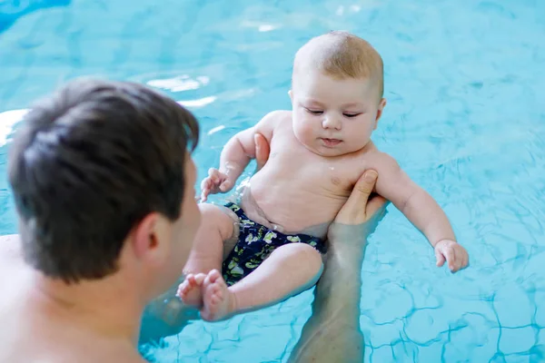 Szczęśliwy ojciec średnim wieku pływanie z cute adorable baby w basenie. — Zdjęcie stockowe