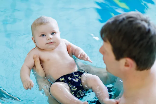 Gelukkig middelbare leeftijd vader zwemmen met schattige schattige baby in zwembad. — Stockfoto