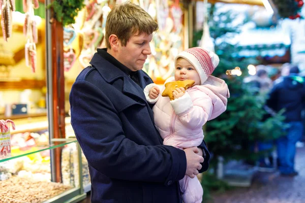 Middelste leeftijd vader dochter meisje van de baby in de buurt van zoete stand met peperkoek en noten te houden. — Stockfoto