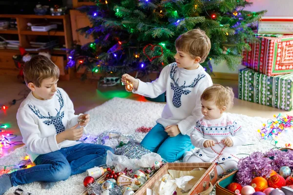 İki küçük çocuk çocuklar ve bebek kız eski vintage oyuncak ve topları ile Noel ağacı süsleme.