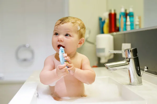 可愛いです可愛い赤ちゃんは洗面台でお風呂に入り、水と泡で遊ぶ — ストック写真