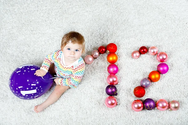 Очаровательная девочка держит красочный винтажный рождественский игрушечный мяч в милых руках. Маленький ребенок и рождественские елки, как двенадцать . — стоковое фото