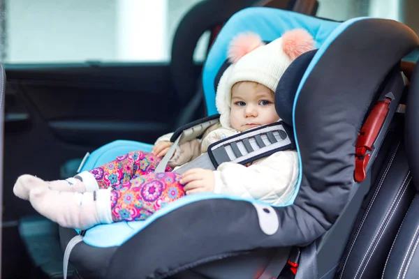 Αξιολάτρευτο κοριτσάκι με μπλε μάτια που κάθεται στο κάθισμα αυτοκινήτου. Νήπιο παιδί σε χειμωνιάτικα ρούχα πρόκειται για οικογενειακές διακοπές και jorney — Φωτογραφία Αρχείου