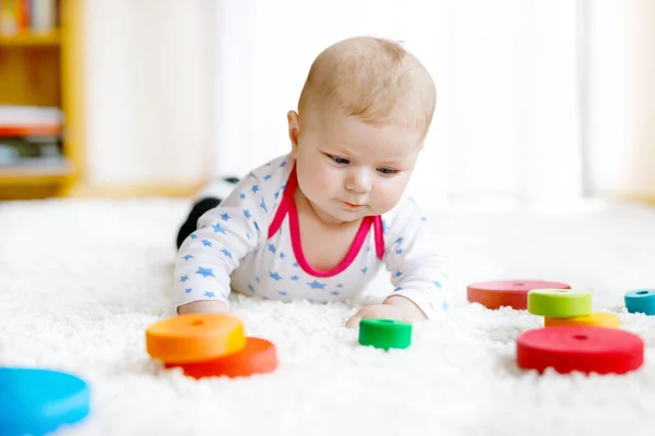 Niedliches kleines Mädchen spielt mit buntem Rasselspielzeug aus Holz — Stockfoto