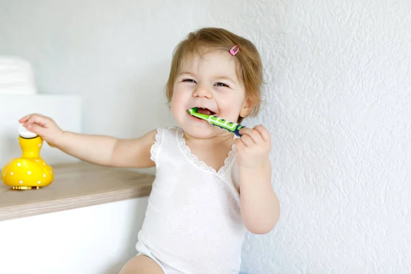 Niña sosteniendo cepillo de dientes y cepillándose los primeros dientes. Niños pequeños aprendiendo a limpiar los dientes de leche. — Foto de Stock