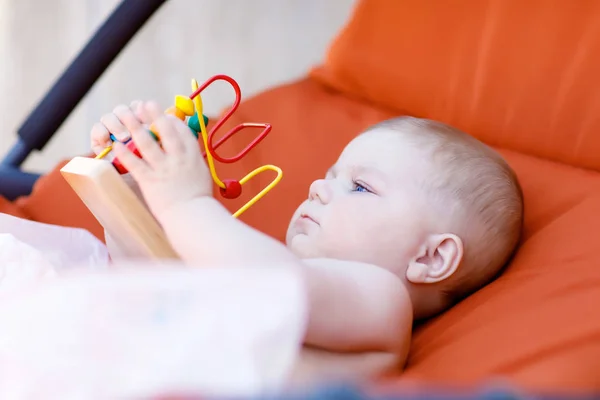 Rozkošný novorozené dítě hraje s barevné chrastítko dřevěná vzdělávací hračka — Stock fotografie