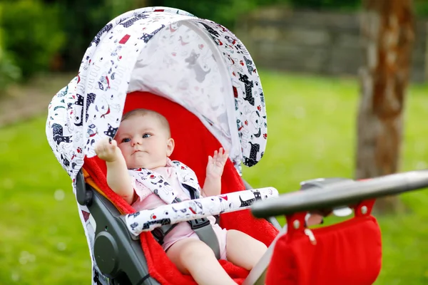 Cute little beautiful baby girl of 6 months sitting in the pram or stroller and waiting for mom — Stock Photo, Image