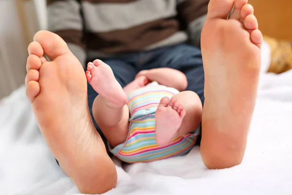 Close-up van enorme voeten van vader en kleine pasgeboren baby — Stockfoto