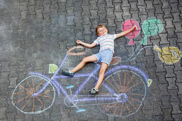 Kleiner Junge hat Spaß mit Fahrradkreiden Bild auf dem Boden — Stockfoto