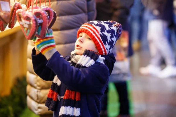 Pequeno garoto bonito menino comprando doces de um stand de cancy no mercado de Natal — Fotografia de Stock