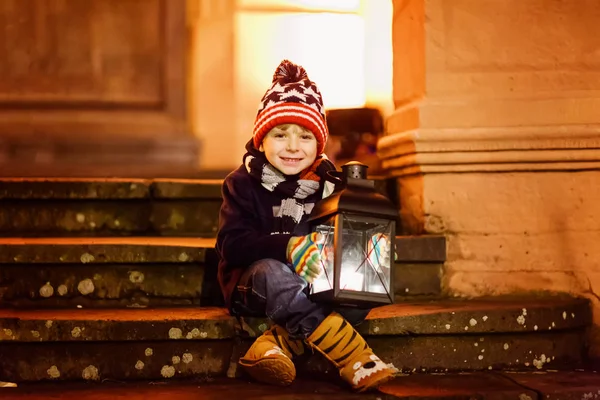 Маленький милый мальчик с фонариком на лестнице возле церкви. — стоковое фото