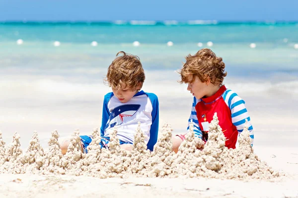 İki küçük çocuk Karayip adasının tropikal sahillerinde kumdan kale inşa ederken eğleniyor.. — Stok fotoğraf