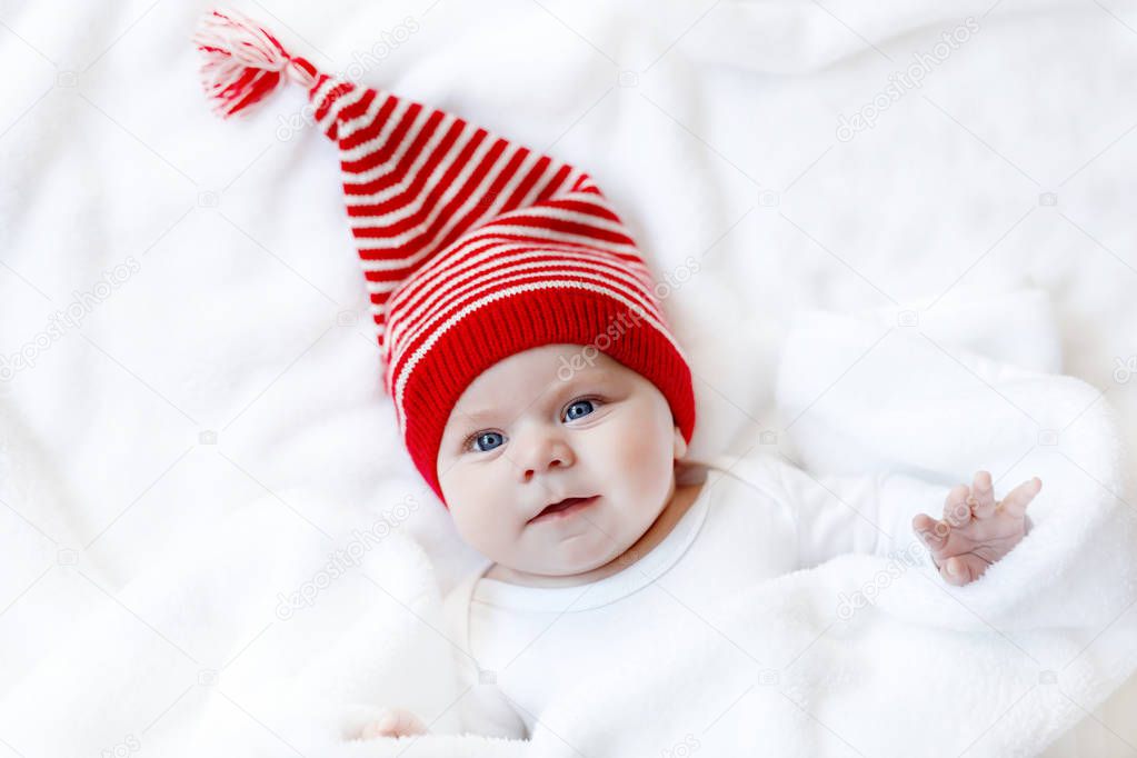 Cute adorable baby child with Christmas winter cap on white background. Happy baby girl or boy smiling and looking at the camera. Close-up for xmas holiday and family concept.