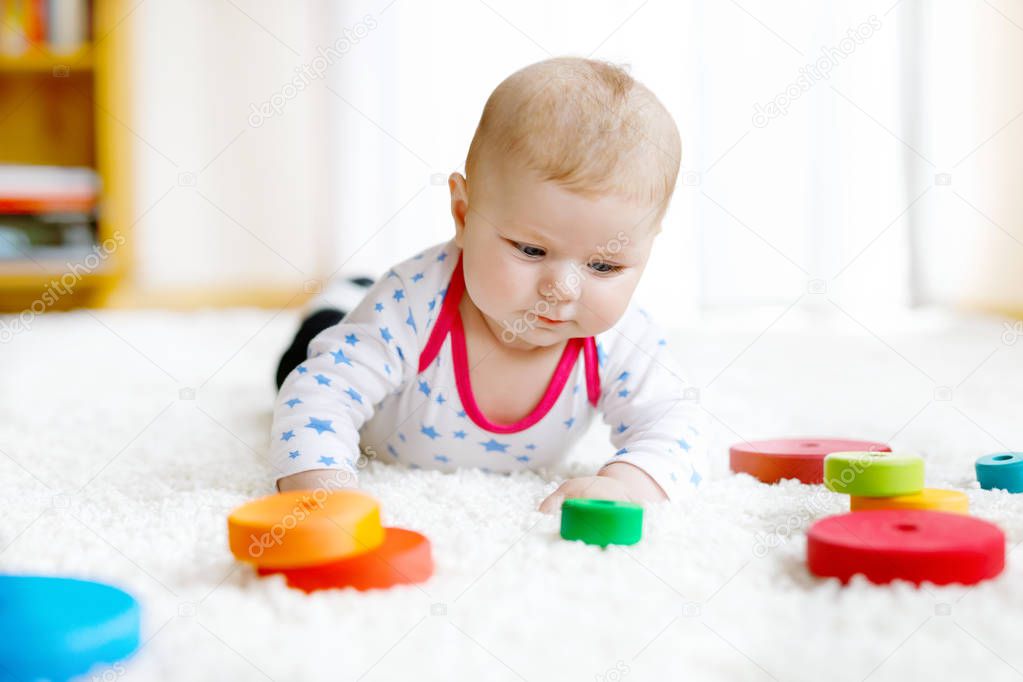 Cute baby girl playing with colorful wooden rattle toy