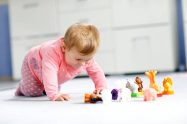 Sevimli bir bebek inek, at, koyun, köpek ve zürafa, fil ve maymun gibi vahşi hayvanlarla oynuyor. Mutlu sağlıklı çocuk evde renkli oyuncaklarla eğleniyor.