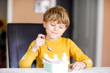Sarışın çocuk ufaklikla kıvırcık saçlar evde ya da anaokulu dondurma yemek. Güzel çocuk büyük dondurma kutusu