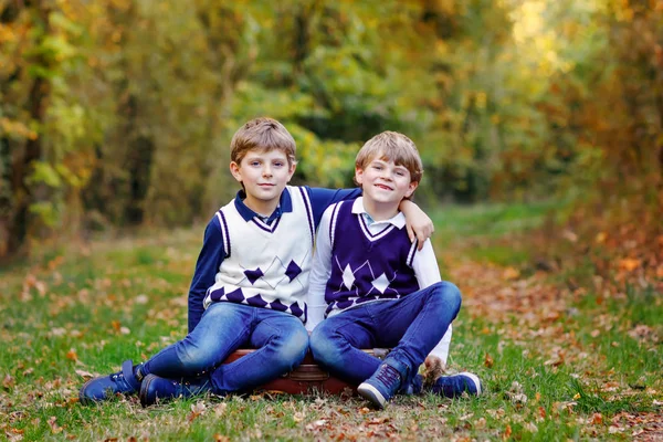Porträt kleiner Schulkinder Jungen sitzen im Wald. fröhliche Kinder, beste Freunde und Geschwister, die sich an einem warmen, sonnigen Frühherbsttag vergnügen. Zwillinge und Familie, Natur und aktive Freizeit. — Stockfoto