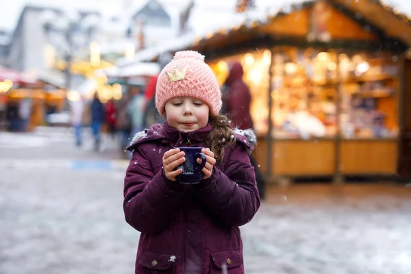 Petite fille mignonne avec une tasse de chocolat chaud fumant ou un coup de poing pour enfants. Joyeux enfant sur le marché de Noël en Allemagne. Loisirs traditionnels pour les familles à Noël . — Photo