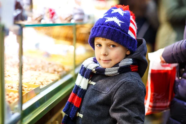Little cute kid boy near sweet stand with gingerbread and nuts. Happy child on Christmas market in Germany. Traditional leisure for families on xmas. Holiday, celebration, tradition, childhood — Stock Photo, Image