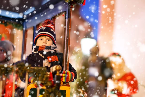 Legrační dítě chlapeček na karuselu na Vánoce lunapark nebo trh, venku. Šťastné dítě baví. Tradiční vánoční trh v Německu, Evropě. Dovolená, děti, životní styl koncept.. — Stock fotografie