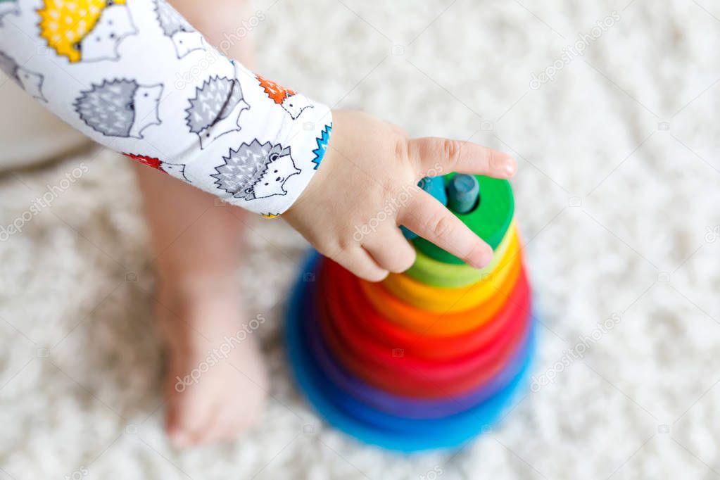 Adorable cute beautiful little baby girl playing with educational wooden toys at home or nursery. Toddler with colorful stack pyramid and music toy. Happy healthy child having fun with different toys