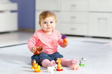 Sevimli bir bebek inek, at, koyun, köpek ve zürafa, fil ve maymun gibi vahşi hayvanlarla oynuyor. Mutlu sağlıklı çocuk evde renkli oyuncaklarla eğleniyor.