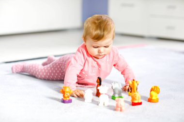 Sevimli bir bebek inek, at, koyun, köpek ve zürafa, fil ve maymun gibi vahşi hayvanlarla oynuyor. Mutlu sağlıklı çocuk evde renkli oyuncaklarla eğleniyor.