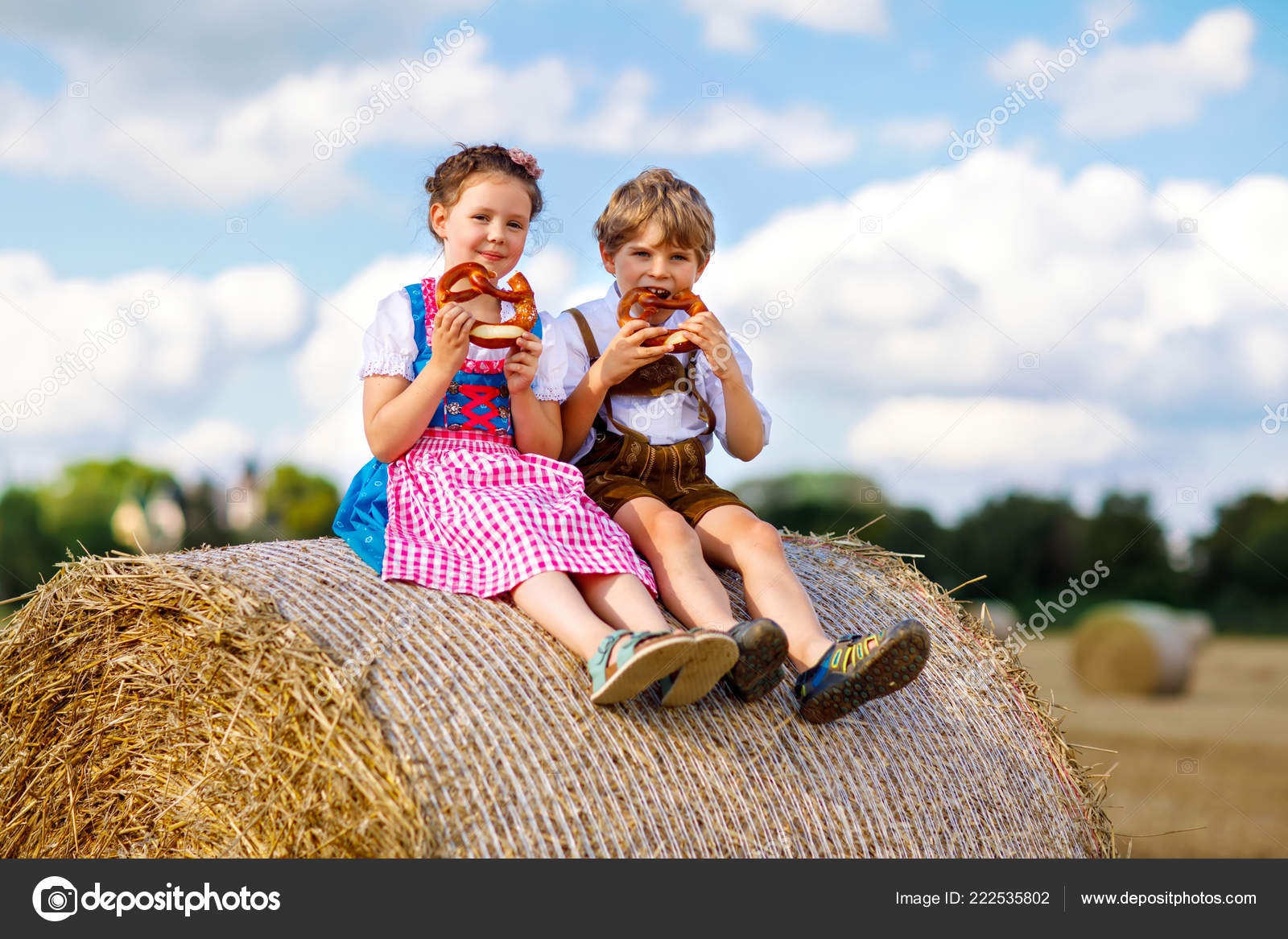 Two kids, boy and girl in traditional Bavarian costumes in wheat field  Stock Photo by ©romrodinka 222535802