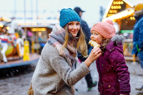 年轻的母亲和女儿吃白色巧克力覆盖水果在传统的德国圣诞市场上串 — 图库照片