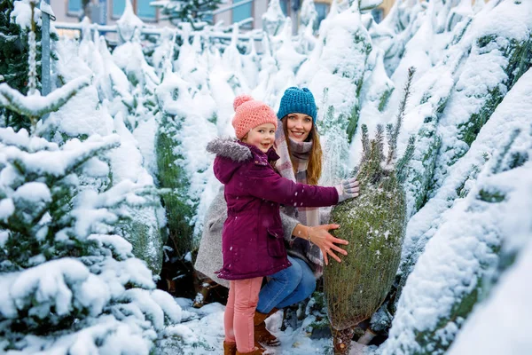 Cute little smiling kid girl and mother on christmas tree market. — Stock Photo, Image