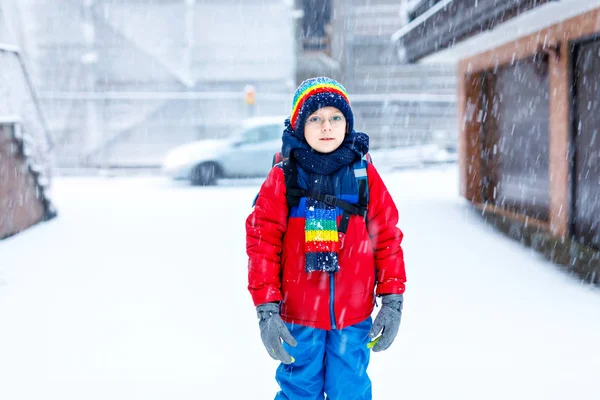 Glücklicher Junge mit Brille hat Spaß mit Schnee auf dem Schulweg, Grundschulklasse — Stockfoto