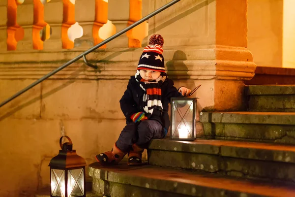 Malý roztomilý chlapec s lucernou na schodech v blízkosti kostela. — Stock fotografie