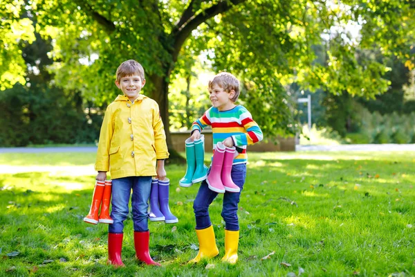 Duas crianças meninos, irmãos bonitos com muitas botas de chuva coloridas. Crianças em diferentes botas de borracha e jaquetas. Calçado para queda chuvosa. Gêmeos saudáveis e melhores amigos se divertindo ao ar livre — Fotografia de Stock