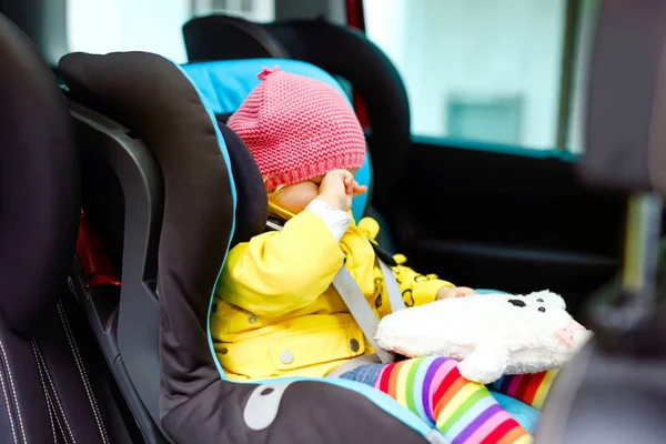 Adorabile stanca piangendo bambina in vestiti colorati seduta in seggiolino auto. Bambino bambino in abiti invernali in vacanza in famiglia e Jorney. auto in ingorgo — Foto Stock