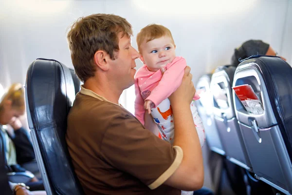 Jonge moe vader en dochter met huilende baby tijdens vlucht op vliegtuig op vakantie te gaan — Stockfoto