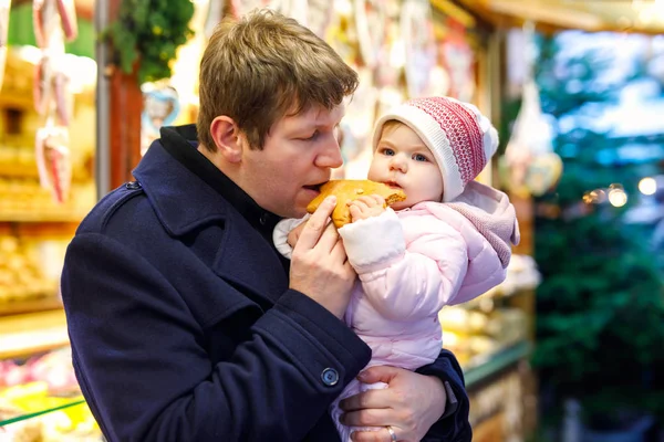 Padre de mediana edad sosteniendo bebé hija niña cerca de soporte dulce con pan de jengibre y nueces . —  Fotos de Stock