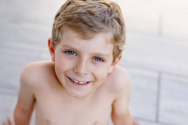 Güneşli yaz gününde gülümseyen güzel çocuk portresi. Mutlu çocuk kameraya bakıyor. Sarı saçlı ve mavi gözlü sevimli bir çocuk.