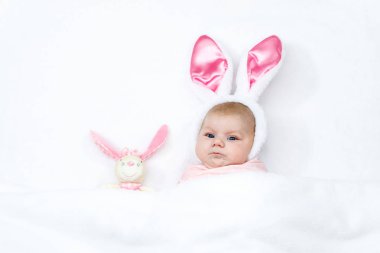 Paskalya tavşanı kostümü ve kulakları olan sevimli yeni doğmuş bebek. Güzel çocuk pelüş tavşan oyuncağıyla oynuyor. Tatil kavramı..