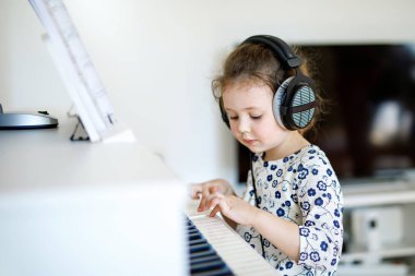 Oturma odasında ya da müzik okulunda piyano çalan güzel bir kız çocuğu. Anaokulu çocuğu müzik aleti çalmayı öğrenirken eğleniyor. Eğitim, beceri kavramı