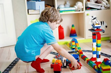 Renkli plastik bloklarla oynama ve tren istasyonu oluşturma sevimli küçük sarışın çocuk çocuk. Tren oyuncak ev bina ile eğleniyor çocuk..